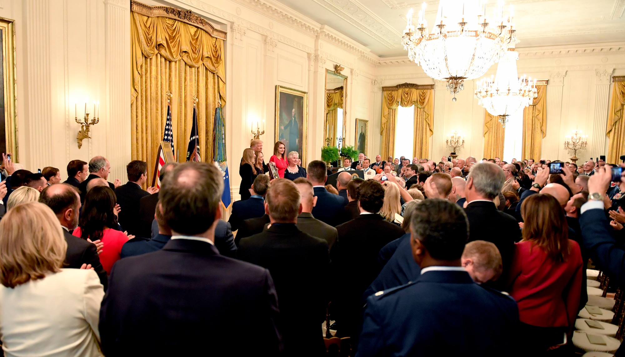 Attendees observe as President Donald J. Trump presents the Medal of Honor to Valerie Nessel, the spouse of U.S. Air Force Tech. Sgt. John Chapman, during a ceremony at the White House in Washington, D.C., June 26, 2018. Chapman was posthumously awarded the Medal of Honor for actions on Takur Ghar mountain in Afghanistan on March 4, 2002, when his elite special operations team was ambushed by the enemy and came under heavy fire from multiple directions. Chapman immediately charged an enemy bunker through thigh-deep snow and killed all enemy occupants. Courageously moving from cover to assault a second machine gun bunker, he was injured by enemy fire. Despite severe wounds, he fought relentlessly, sustaining a violent engagement with multiple enemy personnel before making the ultimate sacrifice. With his last actions, he saved the lives of his teammates. (U.S. Air Force photo by Wayne A. Clark)