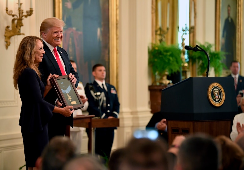 President Donald J. Trump presents the Medal of Honor to Valerie Nessel, the spouse of U.S. Air Force Tech. Sgt. John Chapman, during a ceremony at the White House in Washington, D.C., Aug. 22, 2018. Sergeant Chapman was posthumously awarded the Medal of Honor for actions on Takur Ghar mountain in Afghanistan on March 4, 2002, an elite special operations team was ambushed by the enemy and came under heavy fire from multiple directions. Chapman immediately charged an enemy bunker through thigh-deep snow and killed all enemy occupants. Courageously moving from cover to assault a second machine gun bunker, he was injured by enemy fire. Despite severe wounds, he fought relentlessly, sustaining a violent engagement with multiple enemy personnel before making the ultimate sacrifice. With his last actions he saved the lives of his teammates. (U.S. Air Force photo by Wayne A. Clark)
