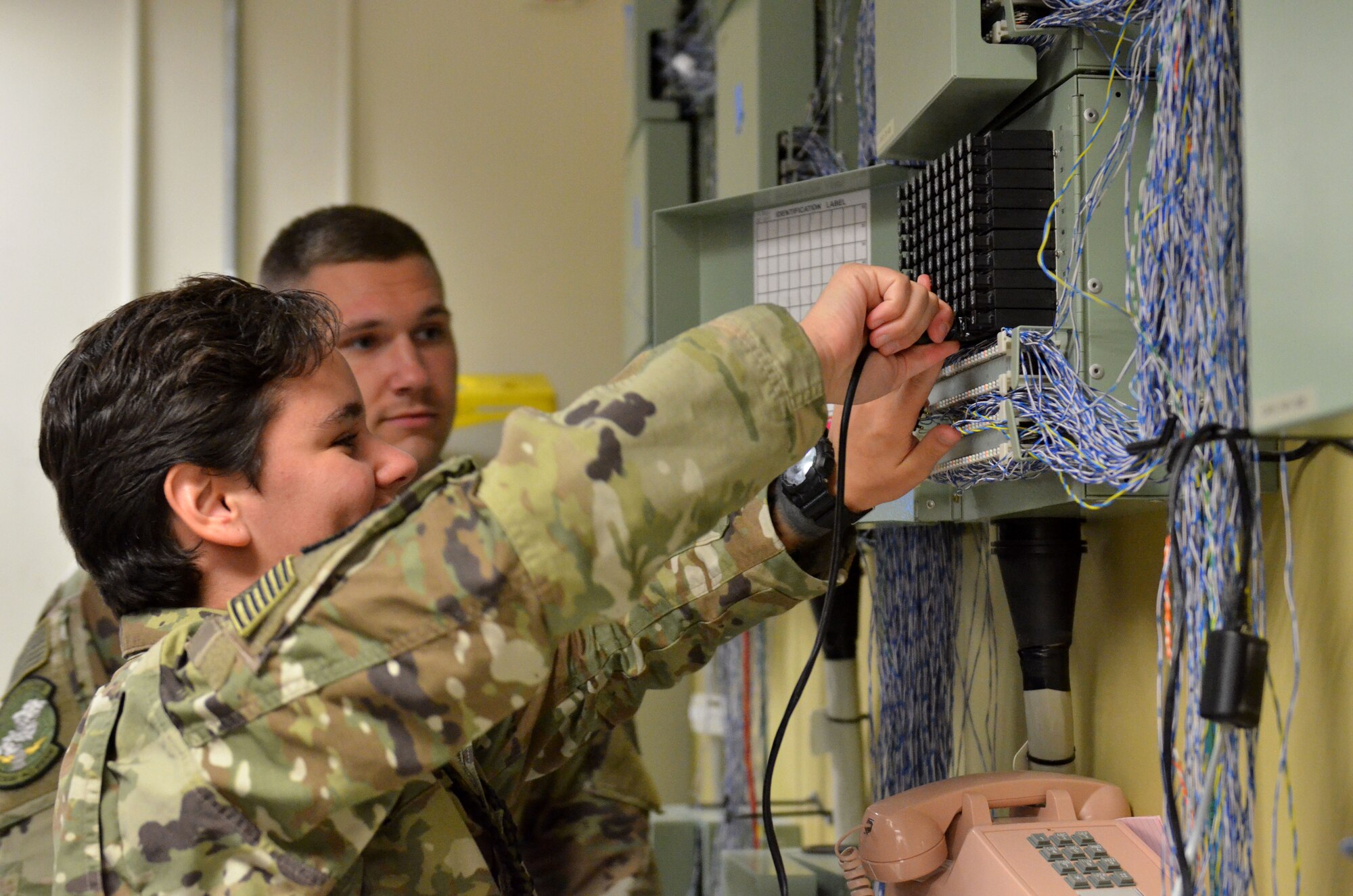 Airman 1st Class Courtney Sherman and Airman 1st Class Tyler Elam, cyber transport technicians assigned to the 609th Expeditionary Air Communications Squadron (EACOMS), check the functionality of phone lines Aug. 8, 2018, at Al Udeid Air Base, Qatar. The 609th EACOMS provides the sole communication support to the Combined Air Operations Center, which is responsible for planning and executing air operations in support of U.S. Central Command (CENTCOM) military objectives in the CENTCOM area of responsibility. (U.S. Air Force photo by Staff Sgt. Caitlin Conner)