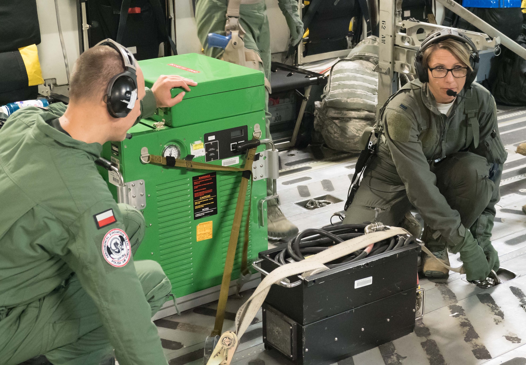 Capt. Marcin Kunicki and 1st Lt. Kay McAmis, 34th AES, Peterson AFB, Colo., secure life support equipment in the C-17 before takeoff.(Air Force Photo/Paul Zadach)