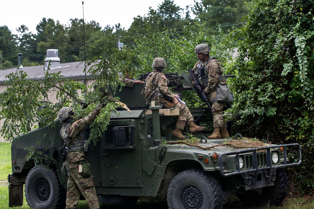 Soldiers camouflage their Humvee during a base security exercise.