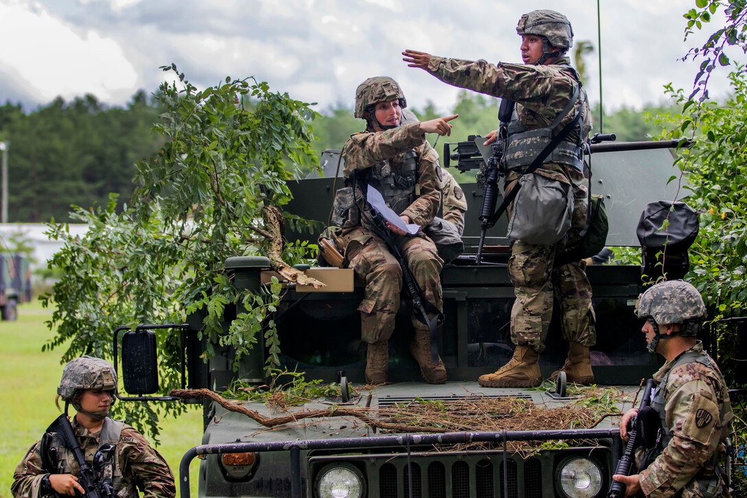 A soldier discusses a convoy route plan with a member of her squad.