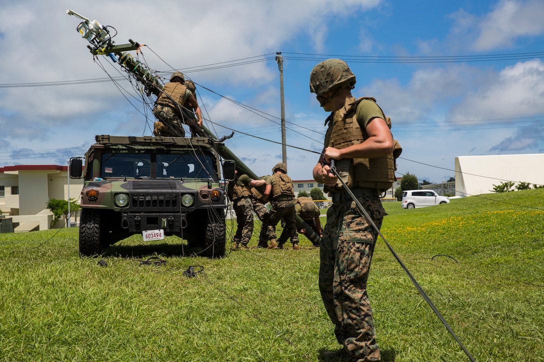 Marines with 7th Communication Battalion, III Marine Expeditionary Force Information Group, lift up a tactical elevated antenna mass mounted with the free space optic system at Camp Hansen, Okinawa, Japan, Aug.17, 2018. Marines are testing the new system, which will allow Marines to transmit mission critical information faster and more securely in environments with damaged infrastructure.