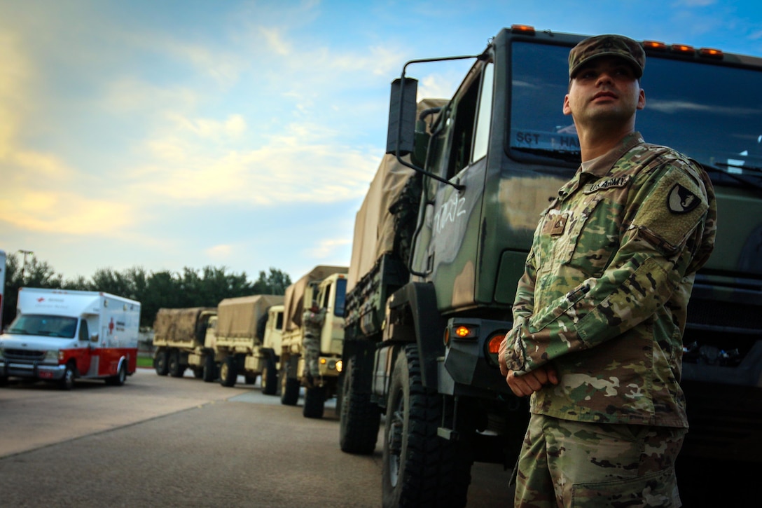 Soldier stands by military truck.