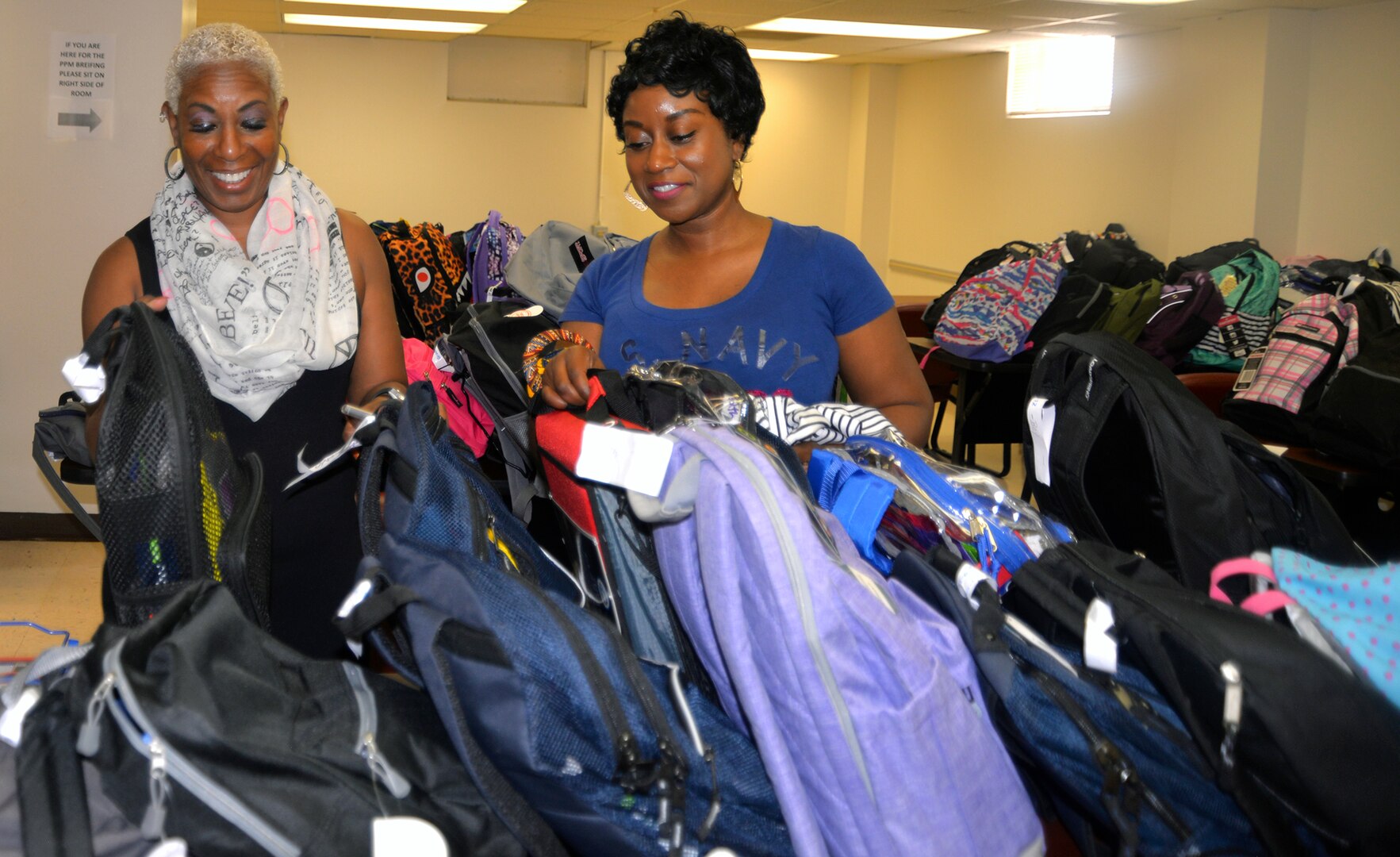 Nita-Ford Hightower (left) and Quiana Abner (right), Joint Base San Antonio-Fort Sam Houston Military Child Education Program school liaison officers, sort through donated backpacks filled with school supplies collected through the eighth annual Build-A-Backpack Program drive Aug. 9. The program, sponsored by the JBSA Military Child Education Program-School Liaison Office, provides backpacks and school supplies for schoolchildren of military families, including active duty and wounded service members and Guard and Reserve personnel. This year, the program provided backpacks for 1,420 JBSA schoolchildren.