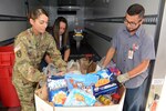 (From left) First Sgt. Julie Morris, U.S. Army Medical Department Center & School Headquarters Support Company, Ms. Ferenie Tinson, HRC Specialist, and Leo Zavala, San Antonio Food Bank truck driver, load a pallet of donated food items.
