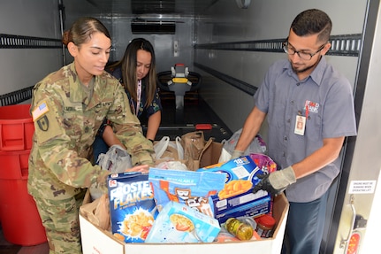 (From left) First Sgt. Julie Morris, U.S. Army Medical Department Center & School Headquarters Support Company, Ms. Ferenie Tinson, HRC Specialist, and Leo Zavala, San Antonio Food Bank truck driver, load a pallet of donated food items.