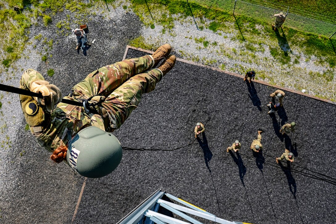 A soldiers descends a rope.