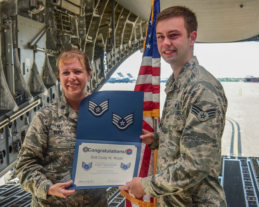 Lt. Col. Karen Rupp, 437th Aerial Port Squadron commander, presents her son, Senior Airman Cody Rupp, 628th Communications Squadron cyber-systems administrator, with a certificate of promotion to the rank of staff sergeant Aug. 21, 2018, at Joint Base Charleston, S.C. The occasion also doubled as a re-enlistment ceremony for Cody Rupp, which was performed by his mother.
