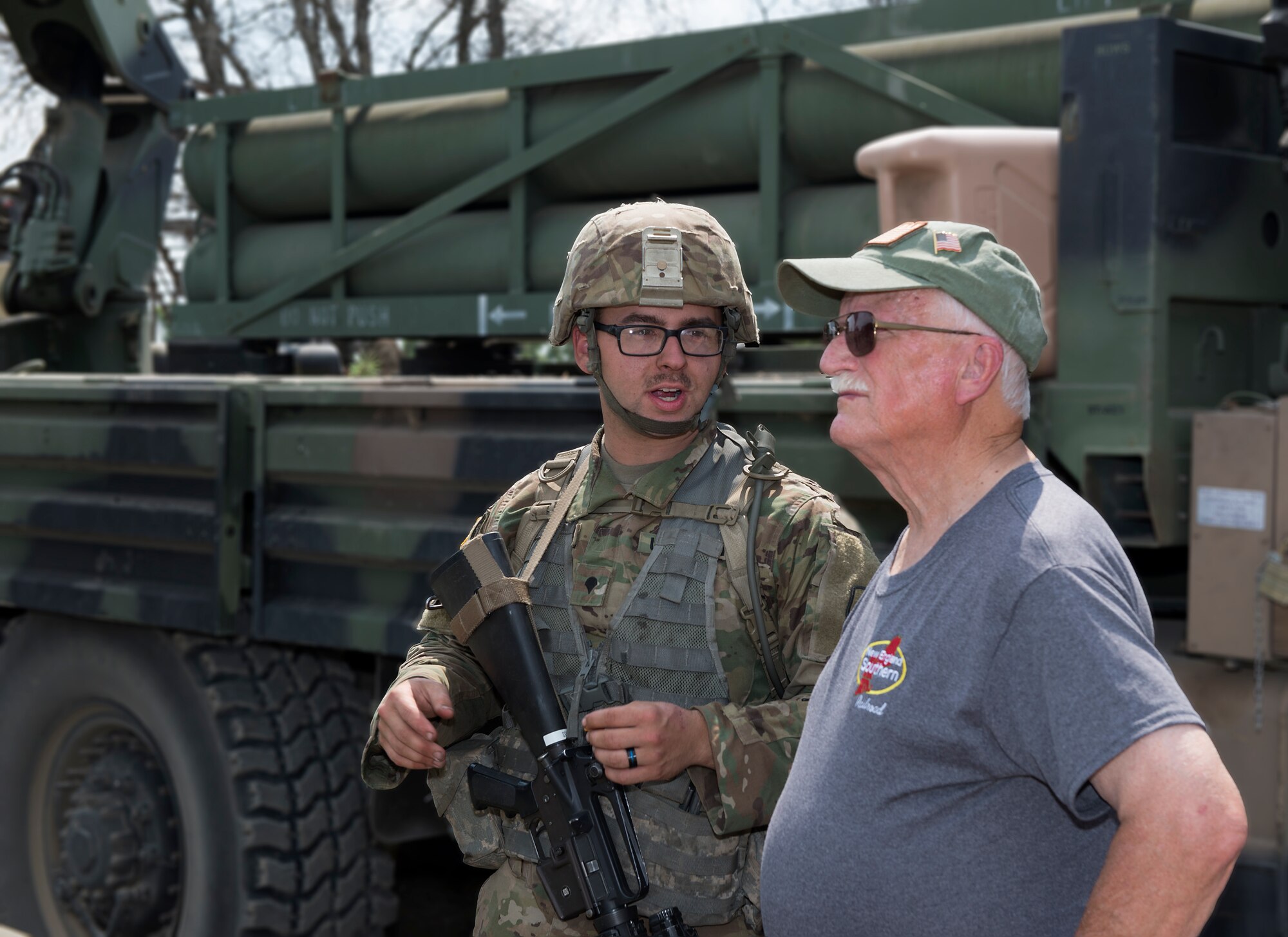 Army Spc. Caulin L. Gagne, a muliti-launch rocket system crewman assigned to the 197th Field Artillery Brigade, answers questions about a weapon system on Aug. 14, 2018 at a traiining site on Camp Grayling, Mich. Peter Dearness, the owner of New England Southern Railroad, visited the 197th FAB during their annual training as part of a tour with the N.H. Employer Support of the Guard and Reserve. (Photo by Staff Sgt. Kayla White, 157th Air Refueling Wing Public Affairs)