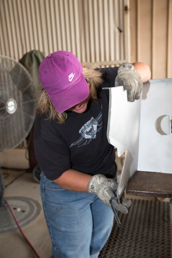 Annette Airo, mobile equipment metal mechanic, straightens a foot rest guard for an amphibious assault vehicle bracket in the Body Shop at Production Plant Barstow, Marine Depot Maintenance Command, on the Yermo Annex aboard Marine Corps Logistics Base Barstow, Calif., Aug. 16. The Body Shop personnel engages in wide array of repairs to include application of fiberglass and bondo, replacing components, and returning items back into serviceable condition.
