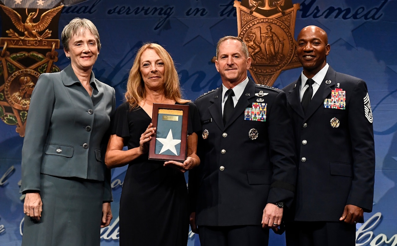 Secretary of the Air Force Heather Wilson, Air Force Chief of Staff Gen. David L. Goldfein and Chief Master Sgt. of the Air Force Kaleth O. Wright present the Medal of Honor Flag to Valerie Nessel, widow of Medal of Honor recipient Tech. Sgt. John Chapman, during Chapman’s Pentagon Hall of Heroes induction ceremony at the Pentagon, in Arlington, Va., Aug. 23, 2018. Chapman was posthumously awarded the Medal of Honor for actions on Takur Ghar Mountain in Afghanistan March 4, 2002. An elite special operations team was ambushed by the enemy and came under heavy fire from multiple directions. Chapman immediately charged an enemy bunker through thigh-deep snow and killed all enemy occupants. Courageously moving from cover to assault a second machine gun bunker, he was injured by enemy fire. Despite severe wounds, he fought relentlessly, sustaining a violent engagement with multiple enemy personnel before making the ultimate sacrifice. With his last actions he saved the lives of his teammates. (U.S. Air Force photo by Staff Sgt. Rusty Frank)