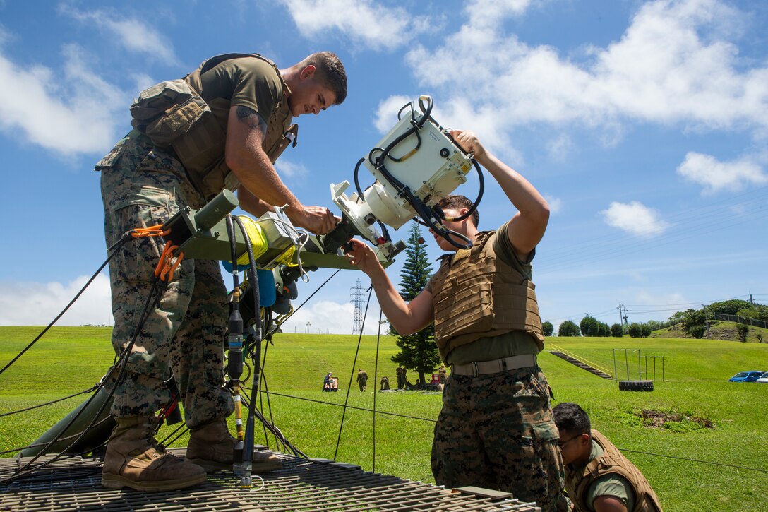 Lance Cpl. Justin Simmons, left, and Lance Cpl. Austin Ruckle, right, both field radio operators with 7th Communication Battalion, III Marine Expeditionary Force Information Group remove the free space optic system from a tactical elevated antenna mass at Camp Hansen, Okinawa, Japan, Aug. 17, 2018.