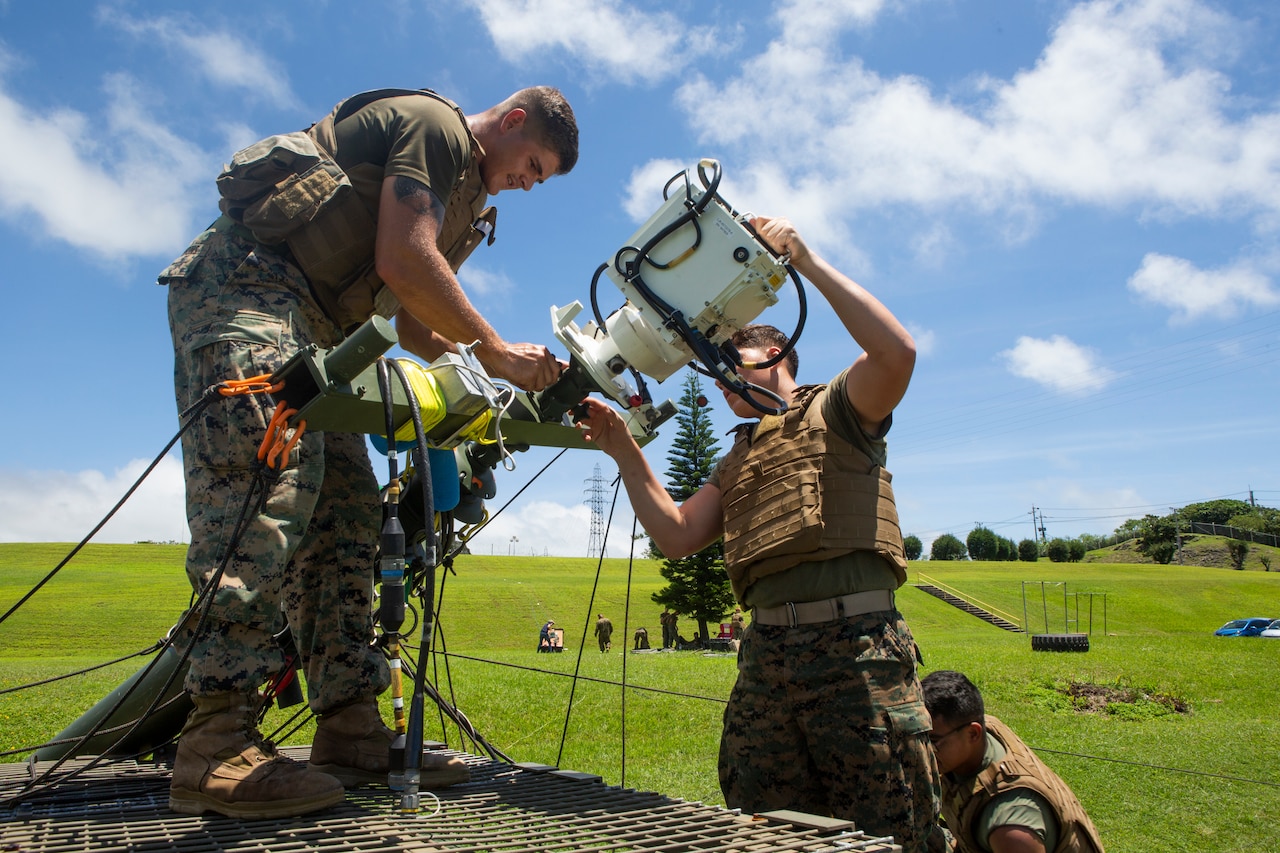 Lance Cpl. Justin Simmons, left, and Lance Cpl. Austin Ruckle, right, both field radio operators with 7th Communication Battalion, III Marine Expeditionary Force Information Group remove the free space optic system from a tactical elevated antenna mass at Camp Hansen, Okinawa, Japan, Aug. 17, 2018.