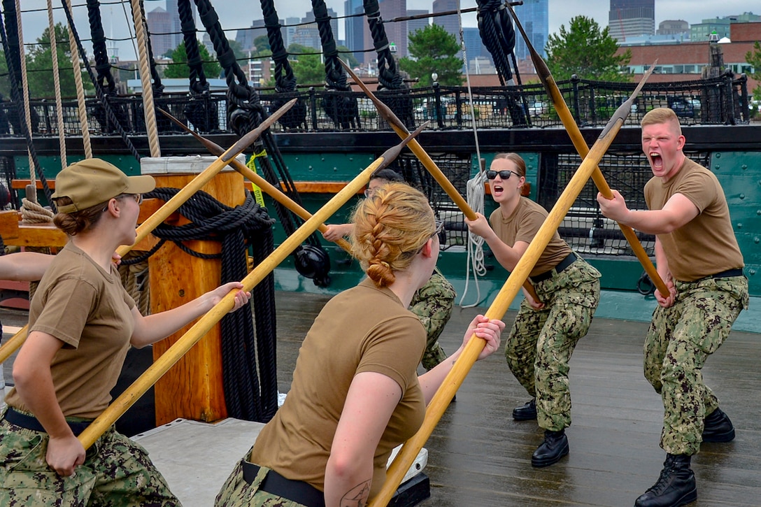 Sailors line up across from each other with pikes.