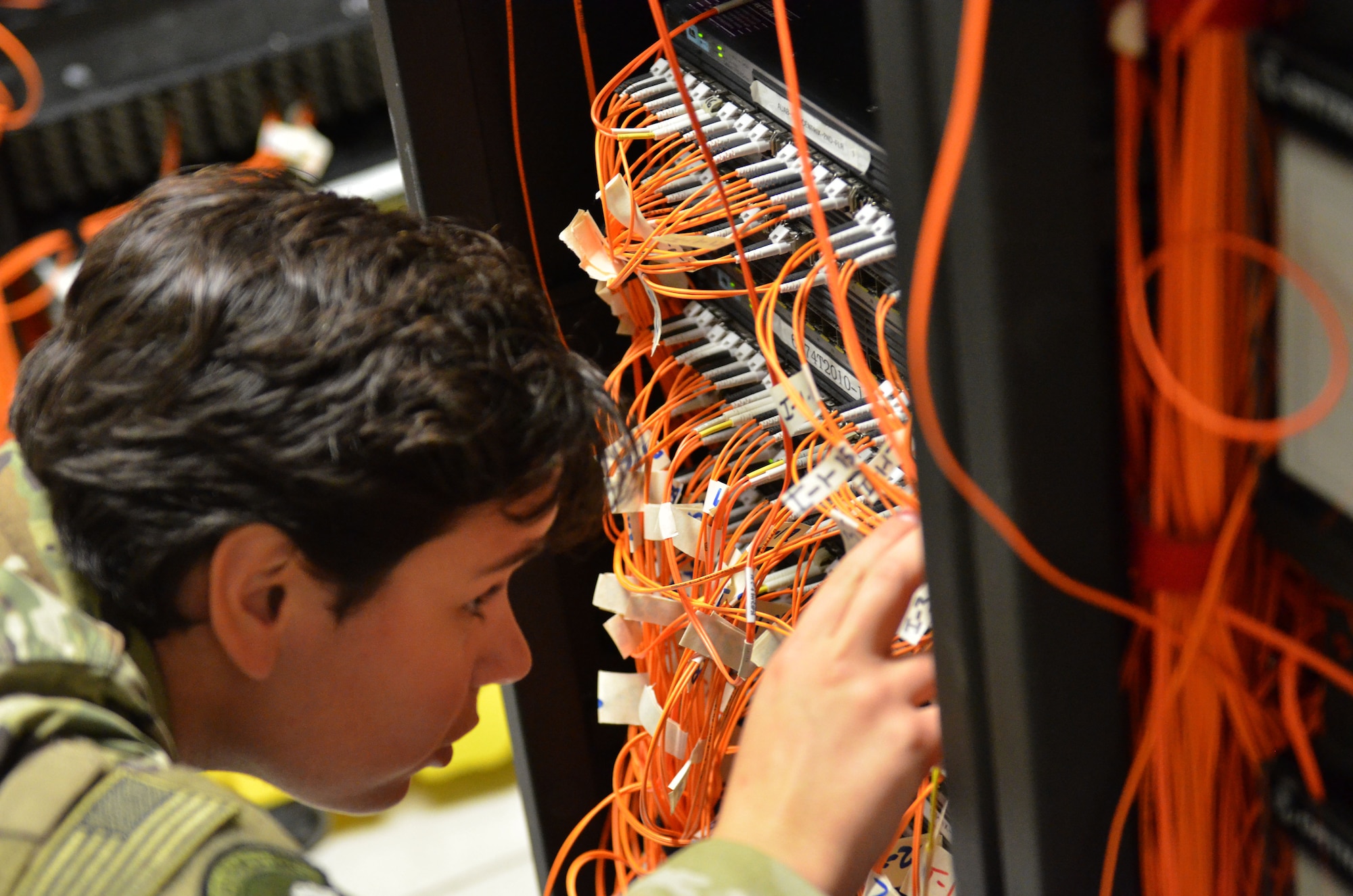 Airman 1st Class Courtney Sherman, a cyber transport technicians assigned to the 609th Expeditionary Air Communications Squadron (EACOMS), traces a fiber cable from a user’s computer to a specific network switch Aug. 8, 2018, at Al Udeid Air Base, Qatar. The 609th EACOMS is the sole communications support for the Combined Air Operations Center which executes air operation missions for U.S. Central Command across a 20 nation area of responsibility. (U.S. Air Force photo by Staff Sgt. Caitlin Conner)