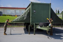 Lance Cpl. William Jenkins unfolds the canopies on an Expeditionary Field Kitchen (EFK) Aug. 24, 2018 on Camp Kinser, Okinawa, Japan.  EFKs are used by food service specialists to cook and distribute food while Marines are deployed and training in the field. Jenkins is a food service specialist with Food Service Company, Headquarters Regiment, 3rd Marine Logistics Group, is a native of Neptune, New Jersey. (U.S. Marine Corps photo by Pfc. Mark Fike)