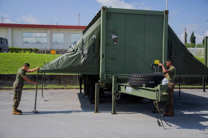 Lance Cpl. William Jenkins unfolds the canopies on an Expeditionary Field Kitchen (EFK) Aug. 24, 2018 on Camp Kinser, Okinawa, Japan.  EFKs are used by food service specialists to cook and distribute food while Marines are deployed and training in the field. Jenkins is a food service specialist with Food Service Company, Headquarters Regiment, 3rd Marine Logistics Group, is a native of Neptune, New Jersey. (U.S. Marine Corps photo by Pfc. Mark Fike)