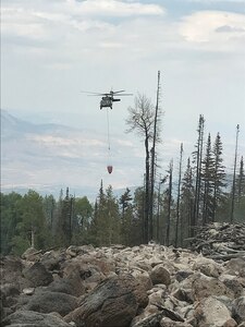 UH-60 Black Hawk helicopters, equipped with aerial water buckets, from the Chief Warrant Officer 5 David R. Carter Army Aviation Support Facility based at Buckley Air Force Base, Aurora, Colorado, drop water on the Cache Creek Fire, in Garfield County, Colorado, to support fire suppression efforts Aug. 17, 2018.
