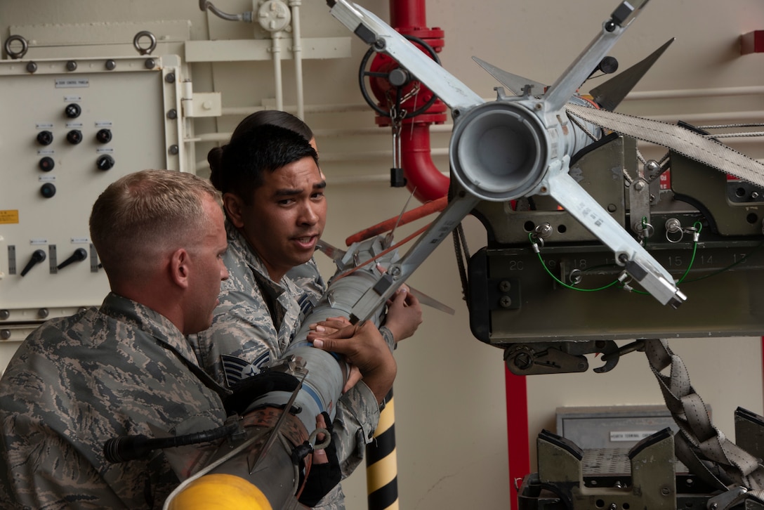 U.S. Air Force Staff Sgt. Bryan Dann, left, 18th Maintenance Group weapons lead crew chief, Tech. Sgt. Jairek Kahai, 18th MXG loading standardization crew member, and Senior Airman Victoria Barsness, 18th MXG weapons lead crew member, demonstrate how to load munitions to an F-15 Eagle during the 2018 Fighter Logistics and Safety Symposium Aug. 21, 2018, at Kadena Air Base, Japan. The symposium enabled air force officers from Australia, Indonesia, Japan, the Philippines, Singapore and Thailand to visit fighter support units assigned to the 18th Wing and interact with Airmen who support the fighter mission. (U.S. Air Force photo by Staff Sgt. Micaiah Anthony)
