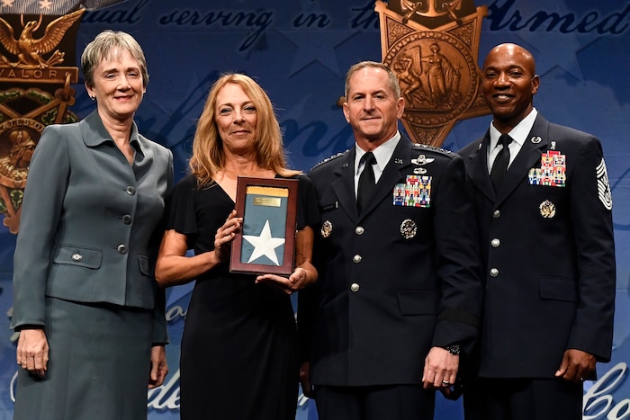 Four people pose for a picture during a ceremony at the Pentagon.