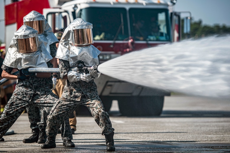 Members from the Naha Air Base fire department test the force of water during joint live-fire training Aug. 7th, 2018, at Kadena AB, Japan. The exercise allowed the 18th Civil Engineer Squadron and Japan Air Self Defense Force to utilize different equipment, and review tactics to putting out fires as part of a knowledge exchange. (U.S. Air Force photo by Airman 1st Class Greg Erwin)