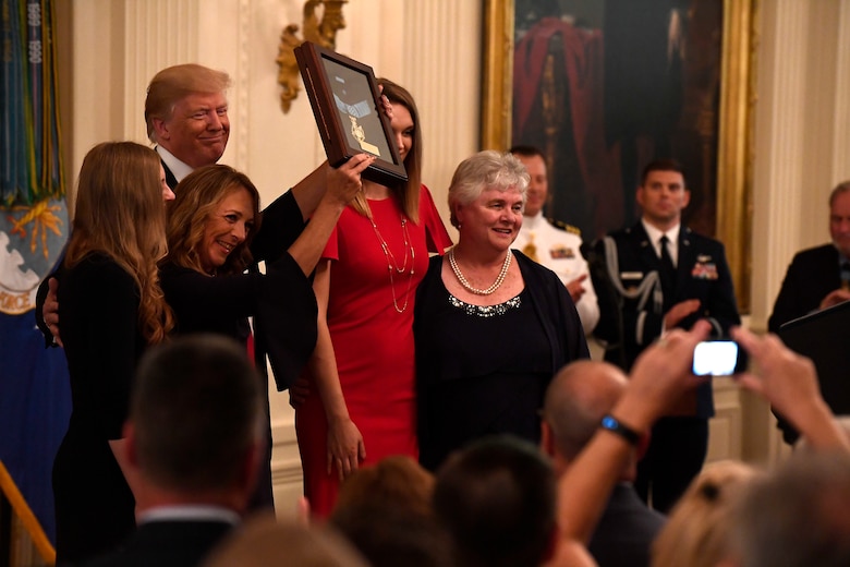 Valerie Nessel, the spouse of Tech. Sgt. John Chapman, holds up the Medal of Honor after receiving it from President Donald J. Trump during a ceremony at the White House in Washington, D.C., Aug. 22, 2018. Chapman was posthumously awarded the Medal of Honor for actions on Takur Ghar mountain in Afghanistan March 4, 2002. His elite special operations team was ambushed by the enemy and came under heavy fire from multiple directions. Chapman immediately charged an enemy bunker through thigh-deep snow and killed all enemy occupants. Courageously moving from cover to assault a second machine gun bunker, he was injured by enemy fire. Despite severe wounds, he fought relentlessly, sustaining a violent engagement with multiple enemy personnel before making the ultimate sacrifice. With his last actions he saved the lives of his teammates. (U.S. Air Force photo by Staff Sgt. Rusty Frank)