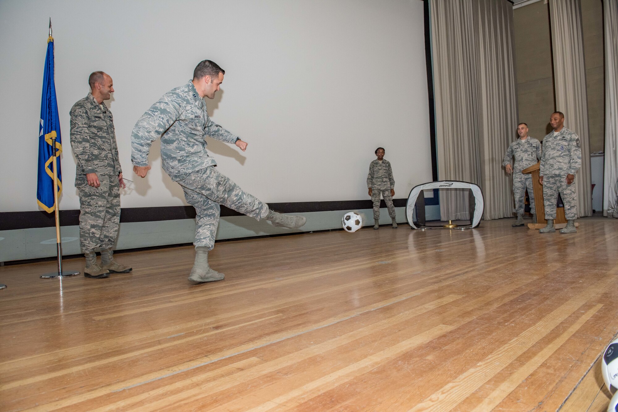 Capt. Matthew Spurgeon kicks a soccer ball into a portable goal during a 412th Test Wing commander's call and second quarter awards ceremony held in the base theater Aug. 23. (U.S. Air Force photo by Matt Williams)