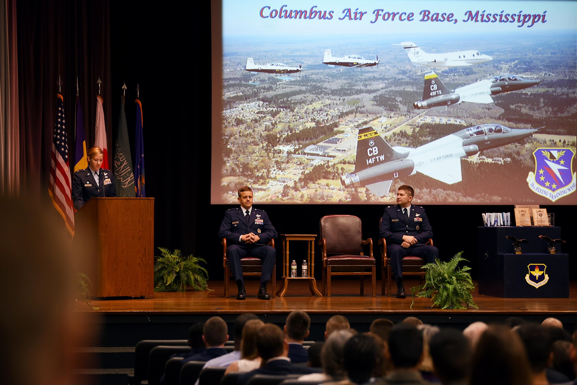 Col. William Denham, 14th Flying Training Wing vice commander and Lt. Col. Ryan Sullivan, 14th Operations Group deputy commander, listen as Col. Samantha Weeks, 14th FTW commander, speaks at Specialized Undergraduate Pilot Training Class 18-13’s graduation Aug. 17, 2018, on Columbus Air Force Base, Mississippi. SUPT class 18-13 was the first graduating class under Weeks’ command. (U.S. Air Force photo by Airman 1st Class Keith Holcomb)