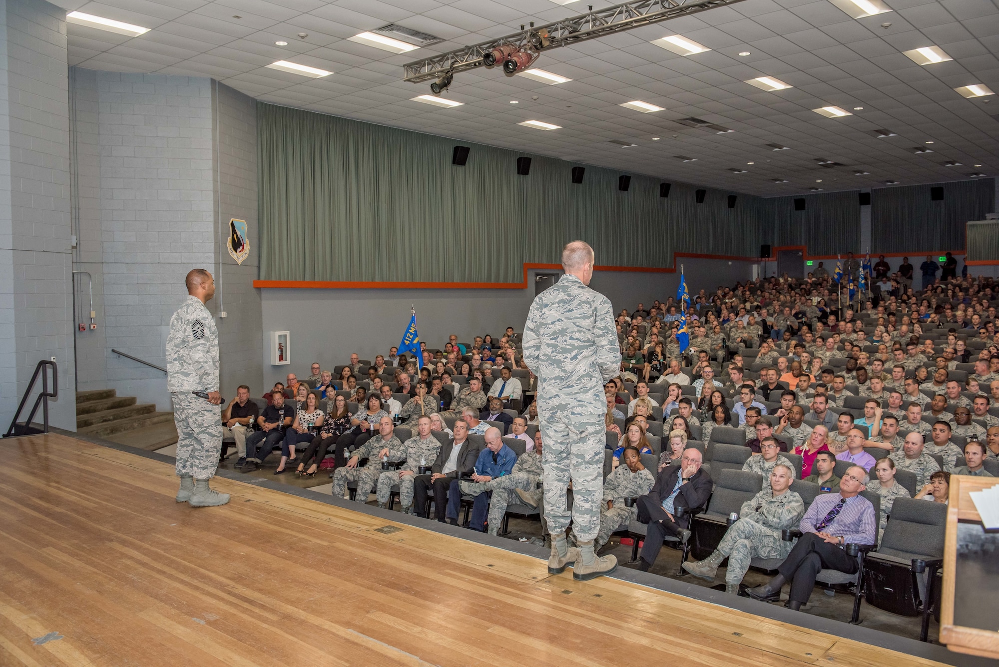 Brig. Gen. E. John Teichert, 412th Test Wing commander, addresses a full base theater Aug. 23 at his first commander's call. Teichert took command of the 412th Test Wing last month. He was accompanied by Chief Master Sgt. Roosevelt Jones, 412th TW command chief (left). (U.S. Air Force photo by Matt Williams)