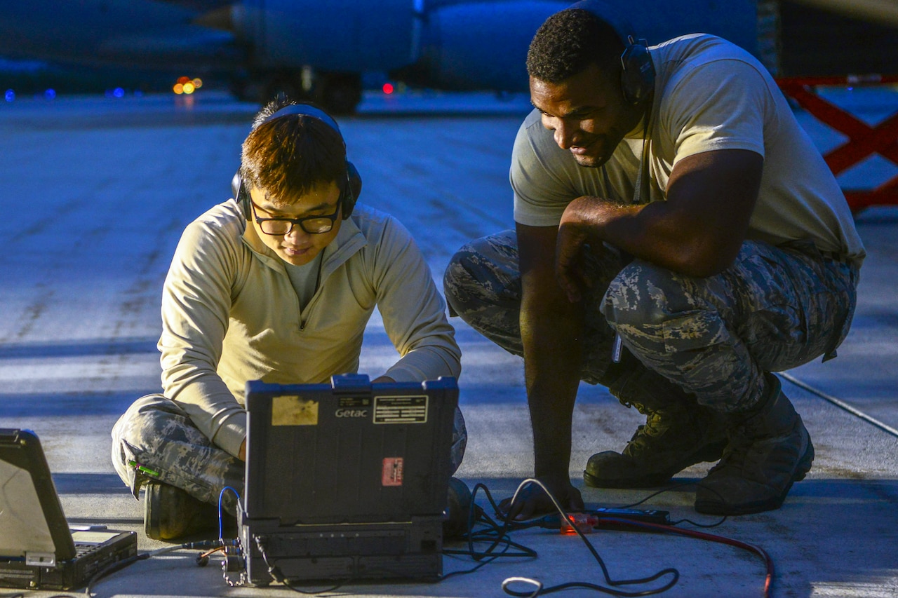 Two airmen read a computer screen together.