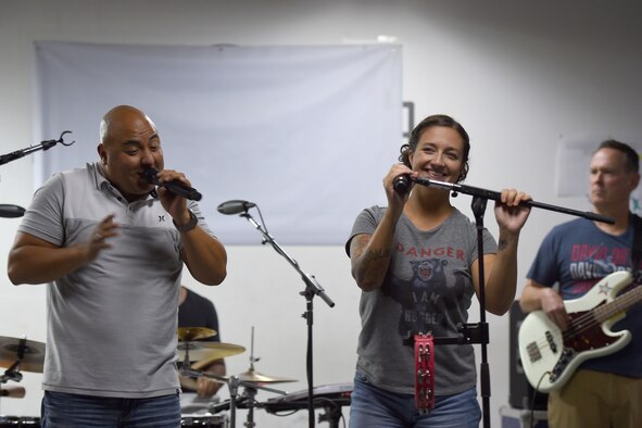 Two Airmen sing on a small stage