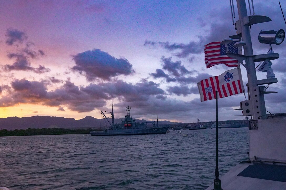 A Coast Guard boat floats off the coast of Hawaii at twilight.