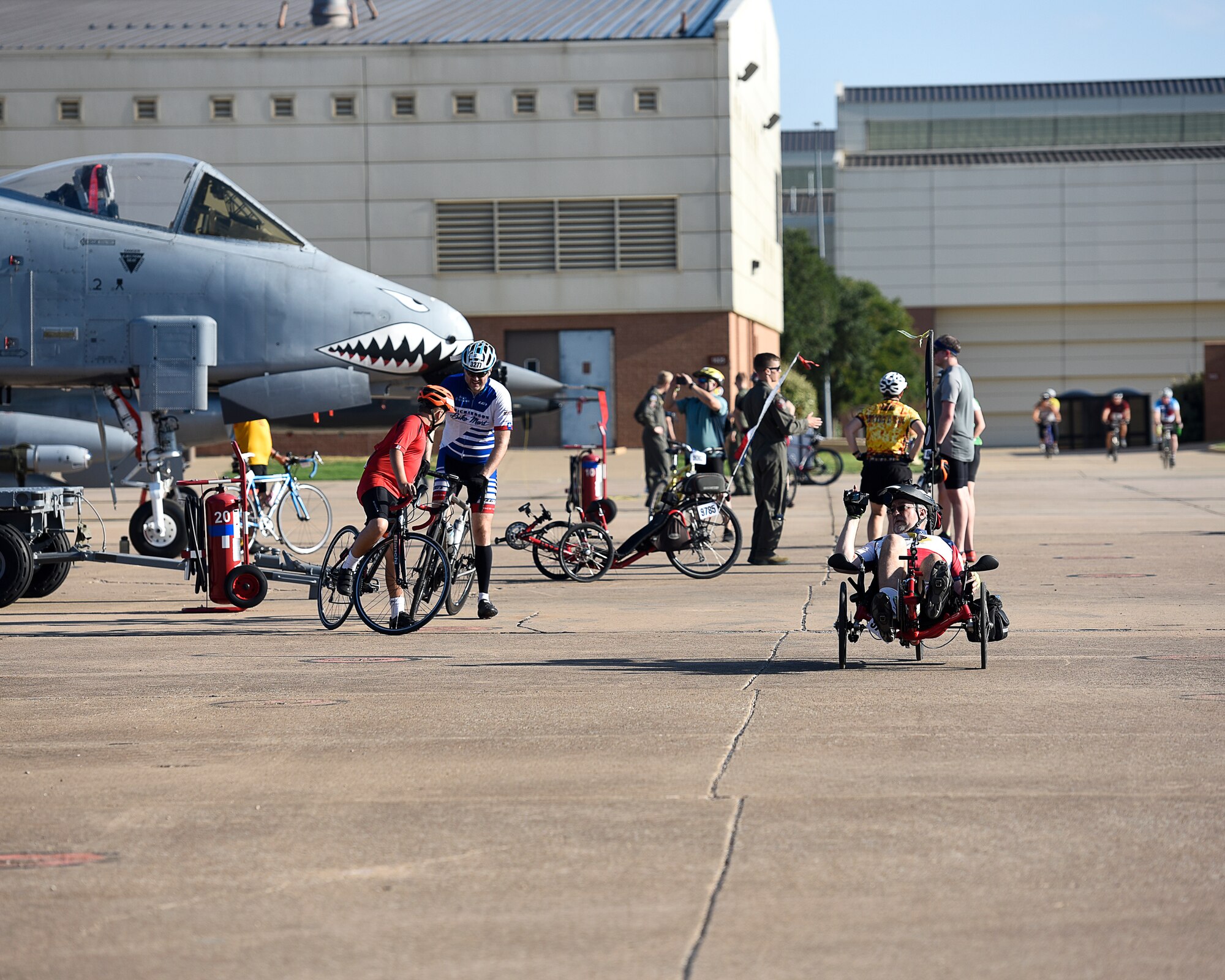 A man on a reclined bike video tapes the aircraft that are set up as part of Airpower Alley.