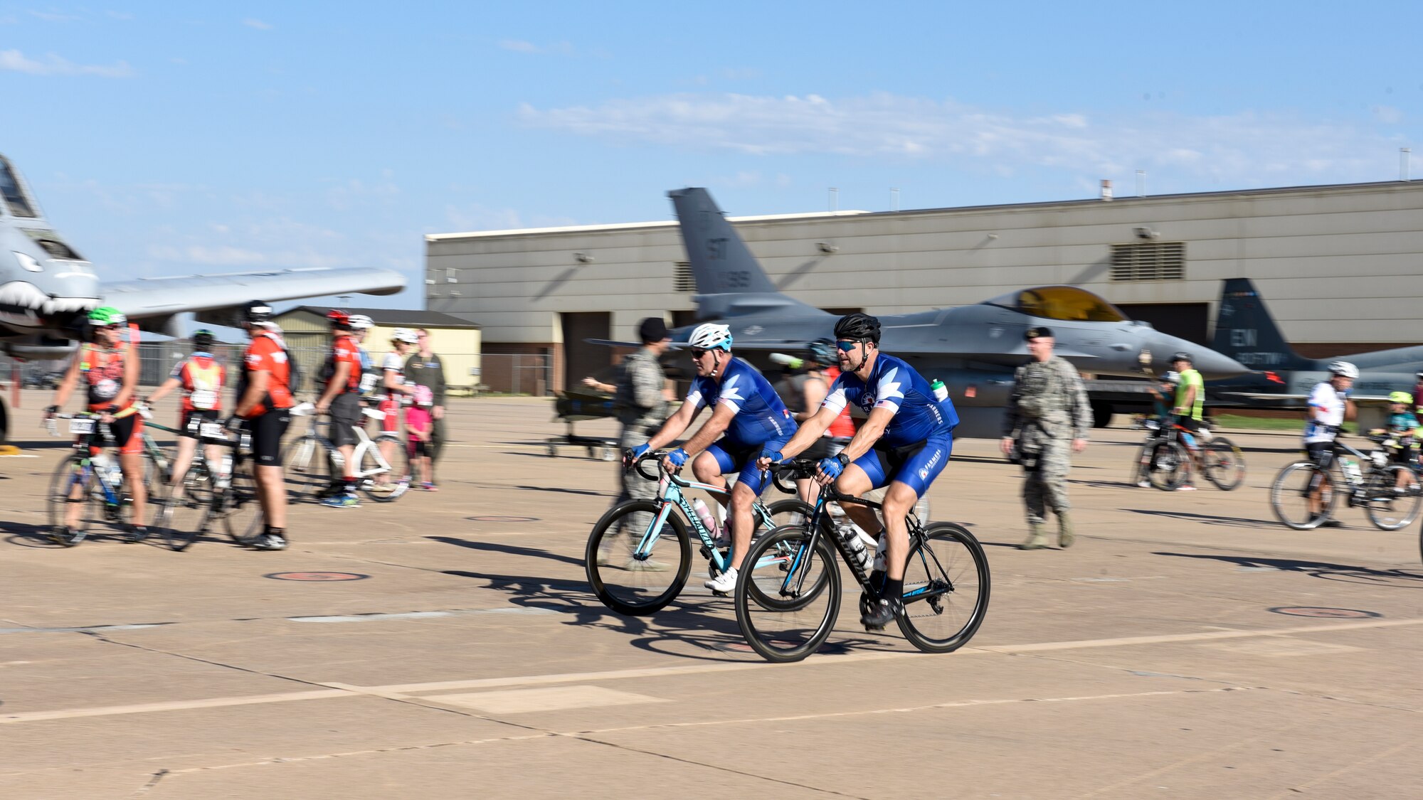 Two bikers in blue pass through Airpower Alley so quickly the background is blurred.