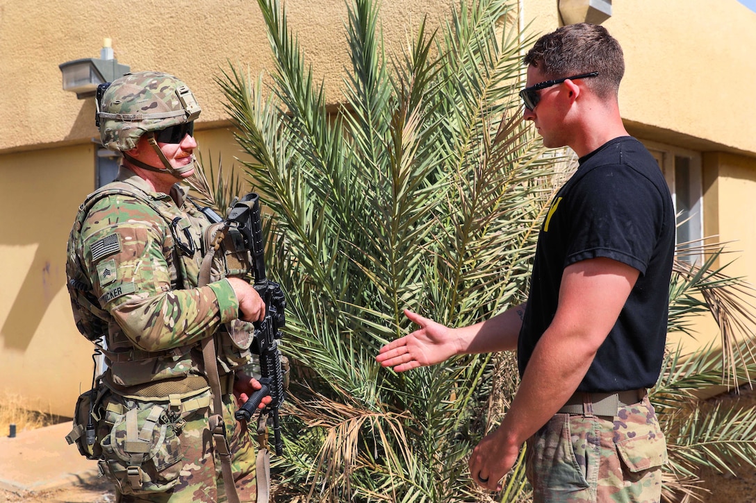 A soldier, left, is approached by another soldier role-playing an opposing force.