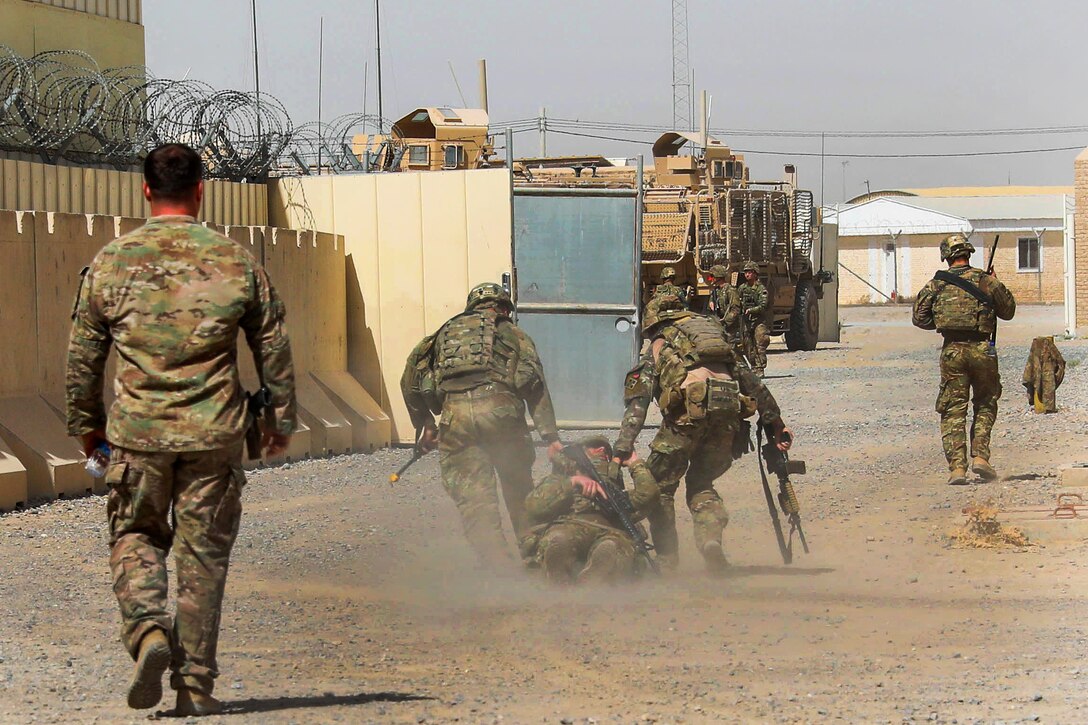 Soldiers drag a role-playing simulated casualty during a Guardian Angel situational training exercise.