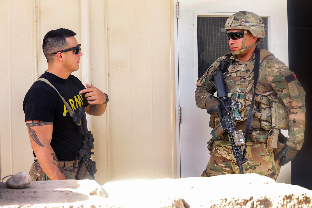 A soldier, right, is engaged by another soldier role-playing as an opposing force, asking for directions.