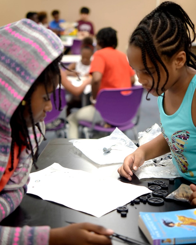 Zariah Dunn and Nia Jackson, students at the Center of Innovation asses’ instructions before building a solar panel toy car at the Youth Center on Joint Base Andrews, Md., July 6, 2018. The COI was transformed in 2015 after receiving funding from the Boys and Girls Club of America and Raytheon to accommodate lessons in science, technology, engineering and math.