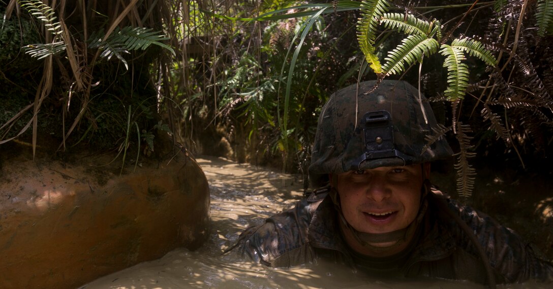Gunnery Sgt. Erik Schwartz crawls though a creek during the endurance course at the Jungle Warfare Training Center in Camp Gonsalves, Okinawa, Japan, August 10, 2018. The obstacle known as the pit and pond requires Marines to crawl through and submerge themselves under water before they can complete the obstacle. Schwartz is with the 4th Assault Amphibian Battalion, 4th Marine Regiment, forward-deployed to 3rd Marine Division as a part of the Unit Deployment Program. (U.S. Marine Corps photo by. Lance Cpl Cameron Parks)