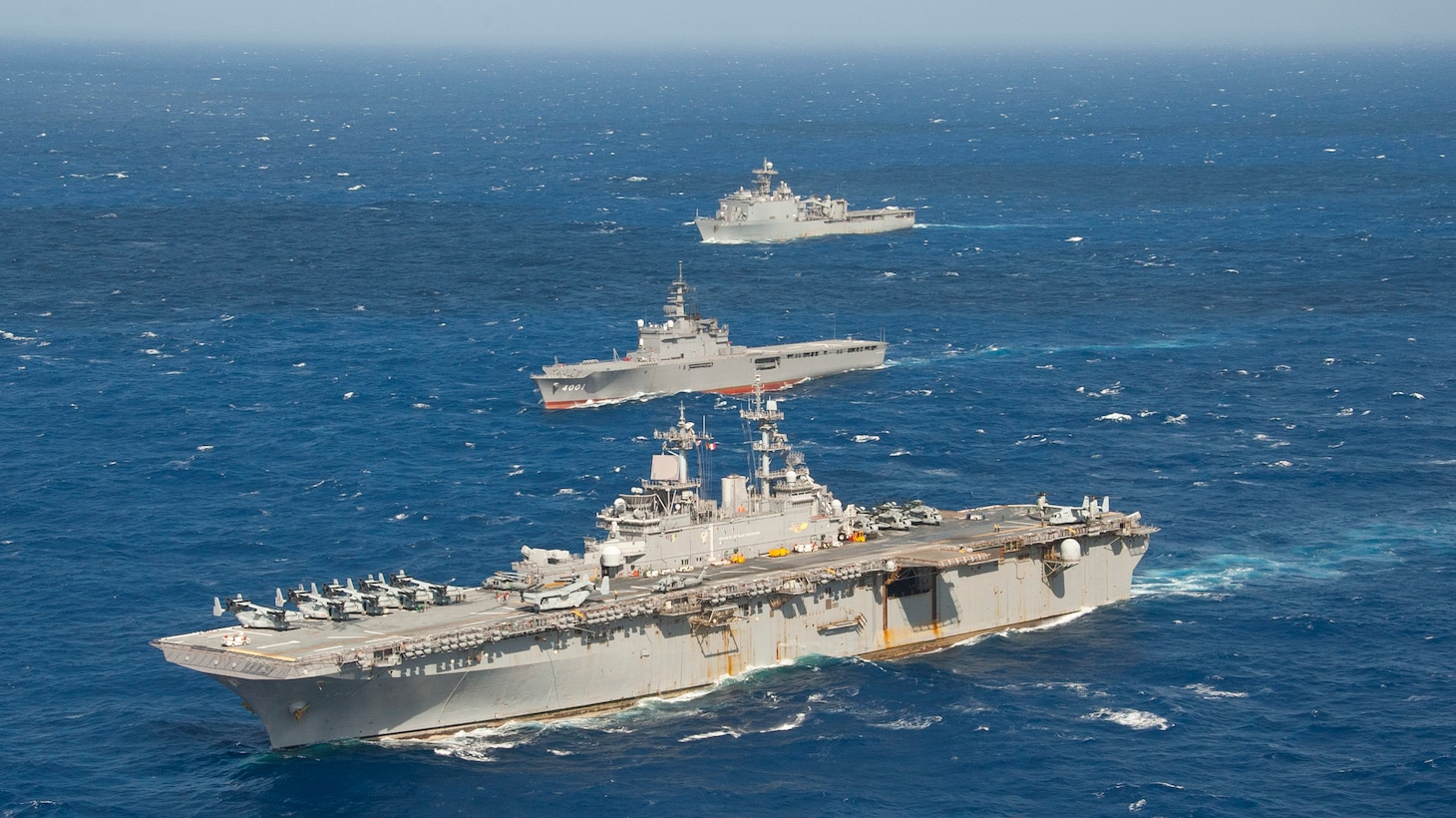 The amphibious assault ship USS Wasp (LHD 1) and dock landing ship USS Ashland (LSD 48), both a part of the Wasp Amphibious Ready Group (ARG), sail alongside the Japan Maritime Self Defense Force (JMSDF) amphibious transport dock ship JS Osumi (LST 4001) during a Passing Exercise (PASSEX) in the Philippine Sea Aug. 26, 2018. PASSEX enabled the Wasp ARG and the JMSDF a chance to practice communications and maneuvering procedures. The Wasp ARG is currently operating in the region to enhance interoperability with partners and serve as a ready-response force for any type of contingency.