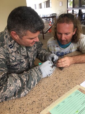 An Air Force nurse removes fishing line from an injured bird.