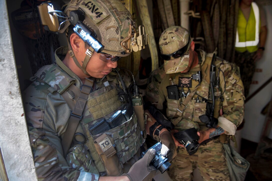 A U.S. sailor and Australian soldier take photographs of evidence while conducting visit, board, search and seizure operations.