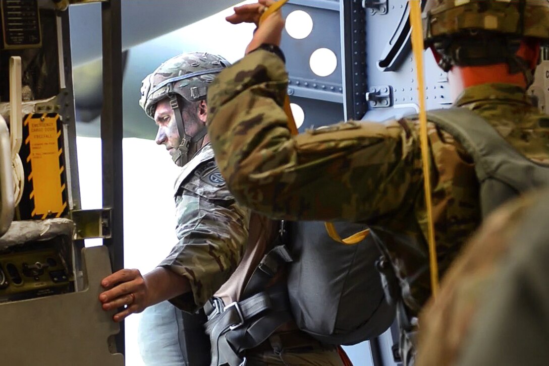 An Army jumpmaster performs a clearance check outside an Air Force C-17 Globemaster aircraft.