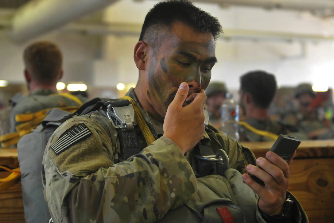 A soldier applies camouflage paint to his face before participating in a static-line airborne operation.