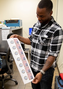 Sean Joyner, a sheet metal mechanic in the Puget Sound Naval Shipyard & Intermediate Maintenance Facility’s Sheet Metal Shop, preps a print-out to create ID tags using the new photo sensitive label plate process. (Photo by Robin L. Lee, PSNS & IMF photographer)