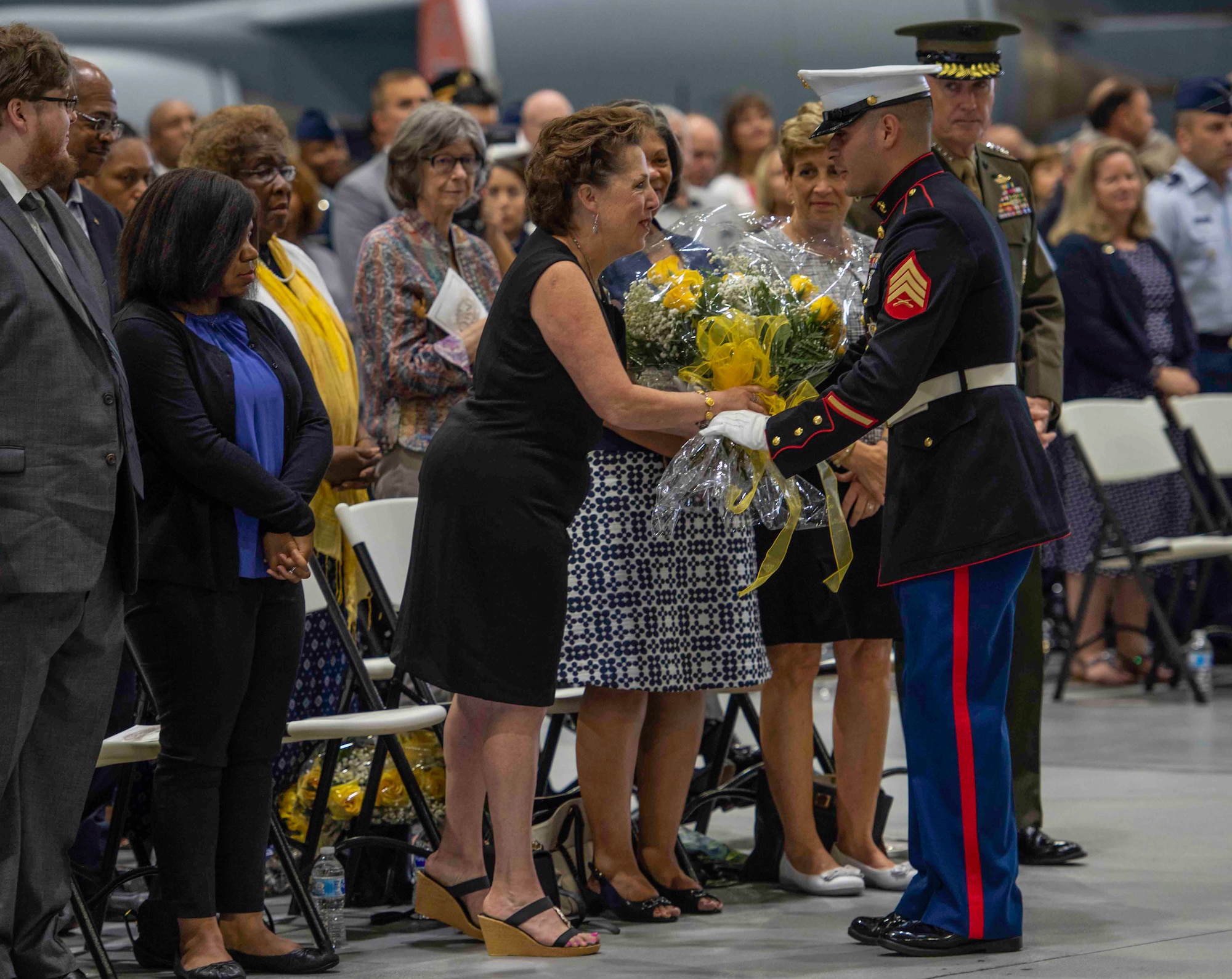 U. S. Marine Sgt. Joel Gonzalez presents a bouquet of yellow roses to Mrs. Maureen Lyons on behalf of the men and women of U.S. Transportation Command.