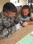 Capt. Mike Yarbrough, a nurse practitioner in the Florida Air National Guard’s 125th Fighter Wing, works to free a bird from tangled fishing line as the bird's caretaker looks on at a health services clinic in Kihei, Hawaii during Tropic Care Maui County 2018, an Innovative Readiness Training mission serving Maui, Molokai and Lanai.