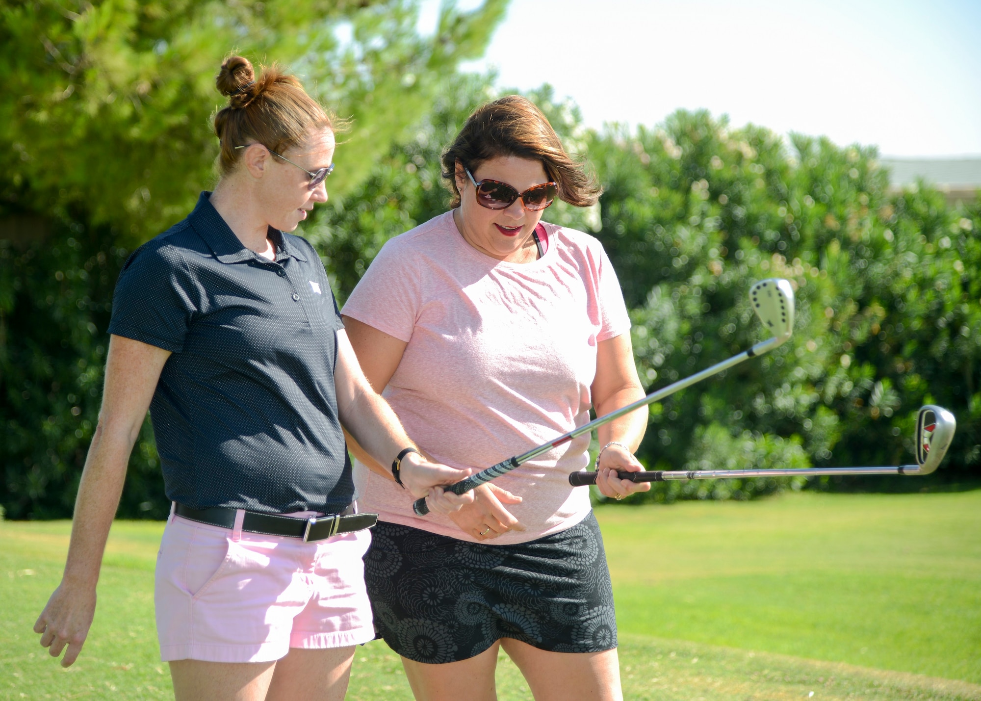 Air Force spouse Melanie Reagan (right) receives basic golfing instruction such as proper club grip from professional golfer Molly Aronsson during a clinic at Muroc Lake Golf Course on Edwards Air Force Base, Aug. 24. (U.S Air Force photo by Giancarlo Casem)