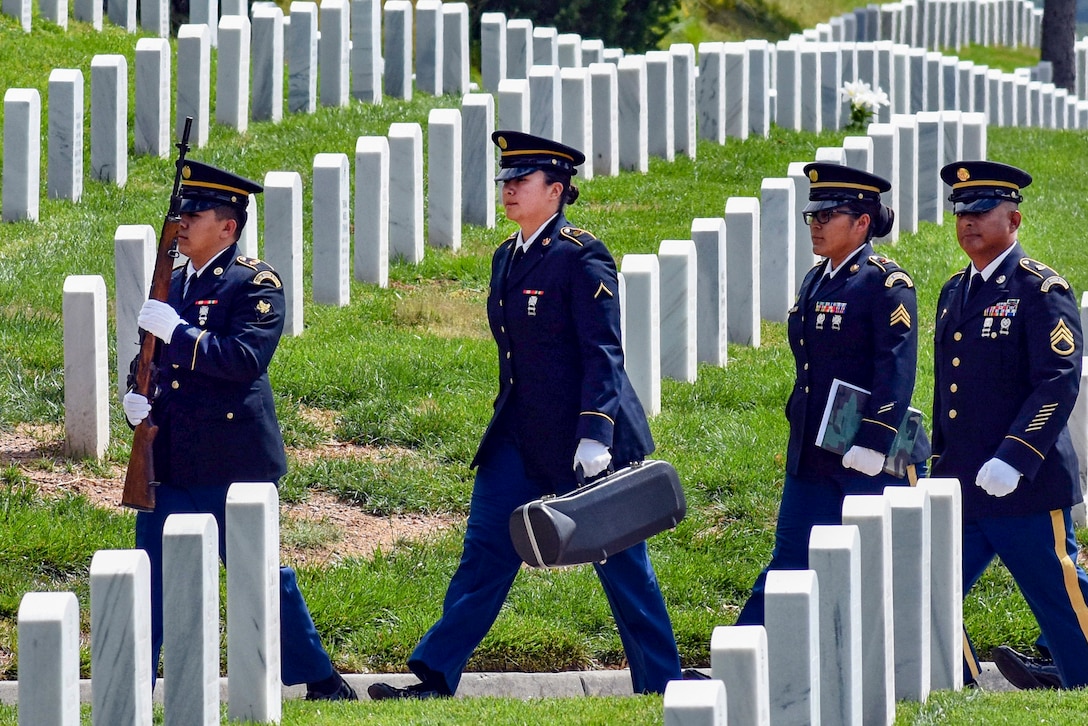 An honor guard walks through a military cemetery.